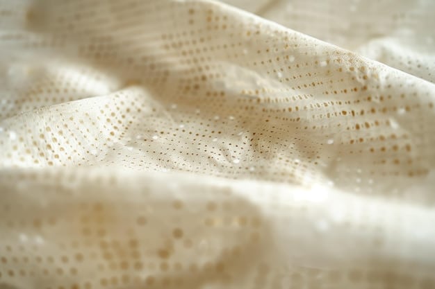 Close-up of organic cotton fabric with a visible, natural texture. The fabric is light-colored and has subtle variations in tone, suggesting a minimally processed material.