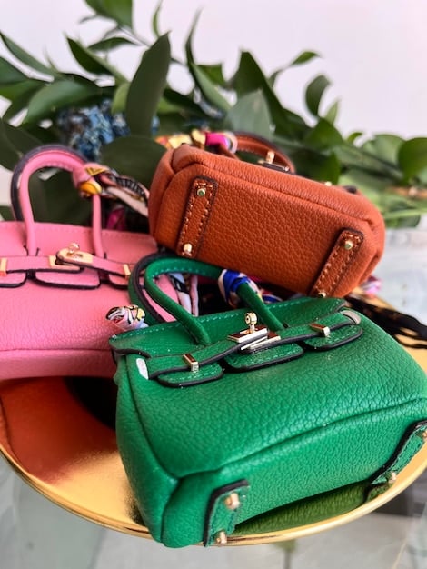 A close-up shot of a variety of stylish handbags from Shein, including a crossbody bag, a tote bag, and a clutch, displayed on a minimalist white shelf. The handbags are in different colors and materials, showcasing the range of options available.