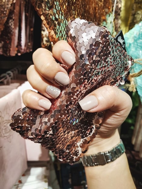 A detail shot of a woman's hands, showing her accessorizing a mixed-print outfit with a neutral-colored belt and delicate gold jewelry. The image emphasizes how accessories can tie together different patterns and add a touch of sophistication.