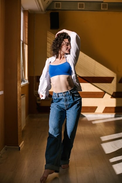 A close-up shot of a woman with an H-shape body type trying on different high-waisted jeans in a well-lit boutique. The focus is on how the high-waist creates an illusion of a more defined waistline.