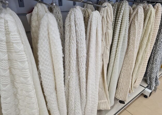 A close-up shot of a well-organized closet featuring neatly folded sweaters in various shades of gray and cream.
