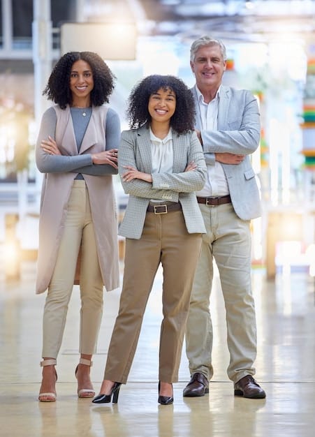 A diverse group of professionals, both men and women, standing in a brightly lit, modern office space in Paris. They are all dressed in stylish yet appropriate attire, including blazers, dresses, and tailored pants. The atmosphere is collaborative and positive, reflecting a modern and inclusive workplace.