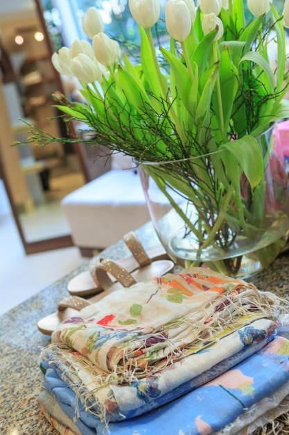 A variety of lightweight fabrics suitable for summer, including silk, cotton voile, and linen. The fabrics are displayed on a sunny windowsill with a view of a garden.