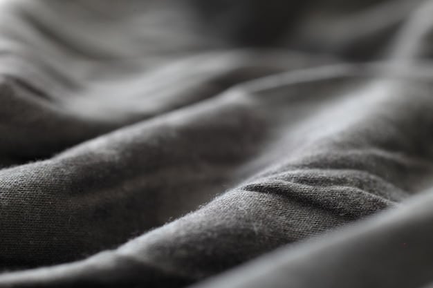 A close-up shot of various textures in a monochrome gray outfit. Focus on the fabrics, including a ribbed knit sweater, smooth wool trousers, and a textured leather belt. The image highlights the subtle contrasts within the monochrome palette, demonstrating how different textures can add depth and interest to a single-color outfit.