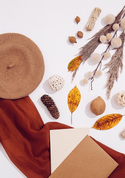 A curated selection of autumn accessories displayed on a minimalist background. The accessories include a structured leather handbag, chunky knit scarf, oversized sunglasses, and ankle boots with a block heel.