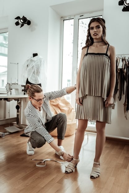 A fashion stylist consulting with a client in a studio, surrounded by clothing racks with winter outfits in the trendy colors of Winter 2025. The stylist is pointing to a specific outfit, giving advice on color combinations and accessories.