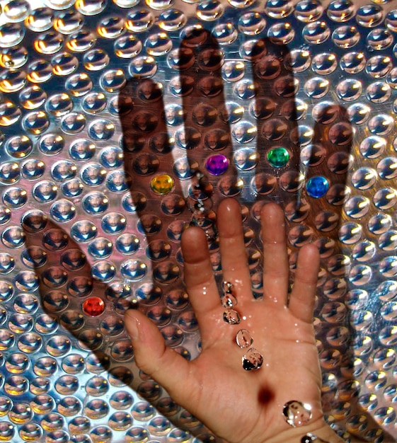 Close-up of a woman's hand adorned with multiple statement rings of varying sizes and materials, including gold, silver, and gemstones. The focus is on the intricate designs and the bold, eclectic styling of the rings.