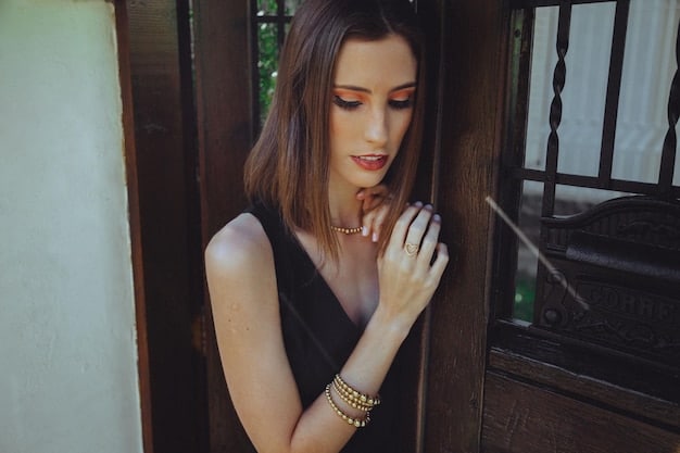 Close up of a woman wearing elegant gold jewelry with a little black dress, showcasing the details of layered necklaces, a cocktail ring, and a delicate bracelet.