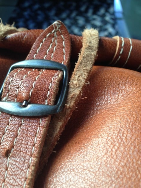 A detailed close-up of a Shein imitation leather belt, showing its buckle and the wear and tear on the imitation leather after six months of use, with visible cracks and color fading.